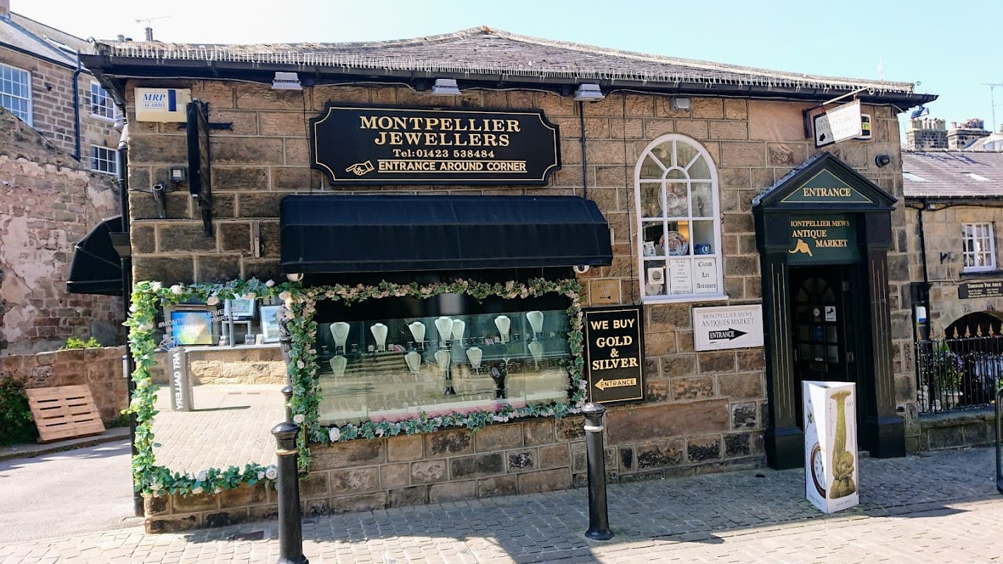 Montpellier Jewellers storefront with a black awning, decorative flowers, and a display of necklaces in the window.