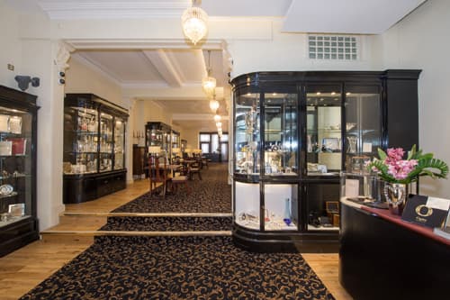Elegant jewellers showcasing glass display cases, polished wooden floors, and decorative lighting in a spacious interior.