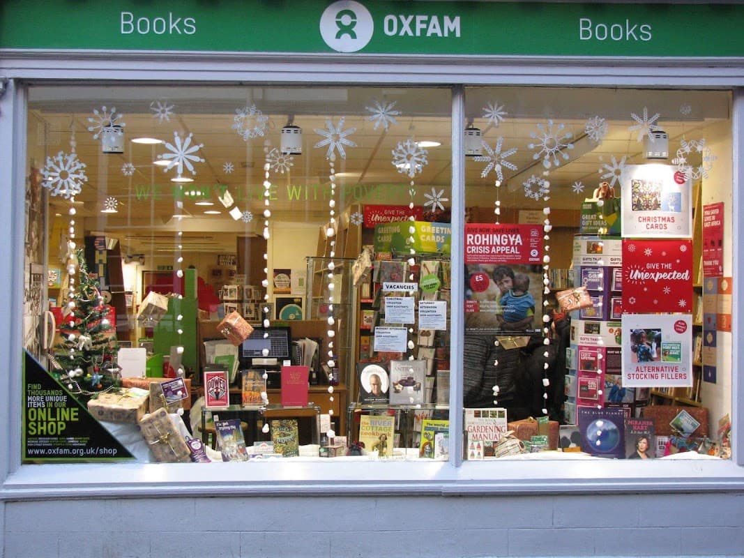 Oxfam Bookshop window display with books, decorations, and a Christmas tree, promoting various charity items.