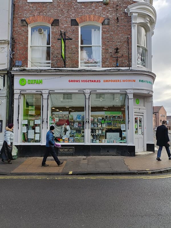 Oxfam bookshop exterior in Harrogate, featuring a large window display and signage promoting social causes.