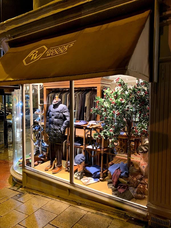 Shoe shop window display featuring clothing, shoes, and a decorative tree in Harrogate, Yorkshire.
