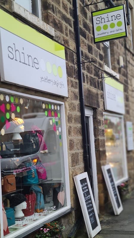 Jewellery shop "Shine" with colorful window displays, bags, and signs in a stone building in Harrogate, Yorkshire.