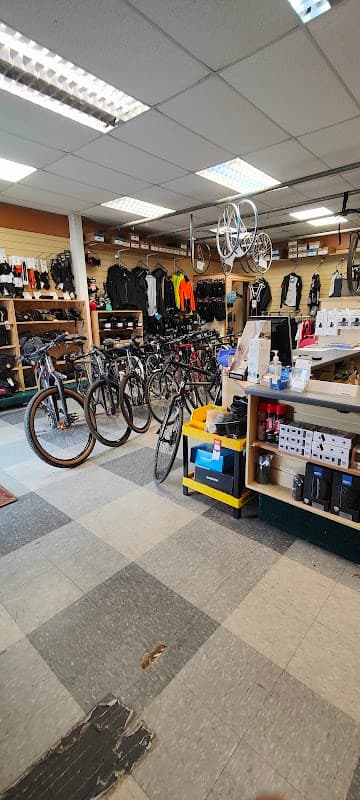 Bikes on display in a shop with shelves of cycling gear and accessories in a spacious, well-lit interior.