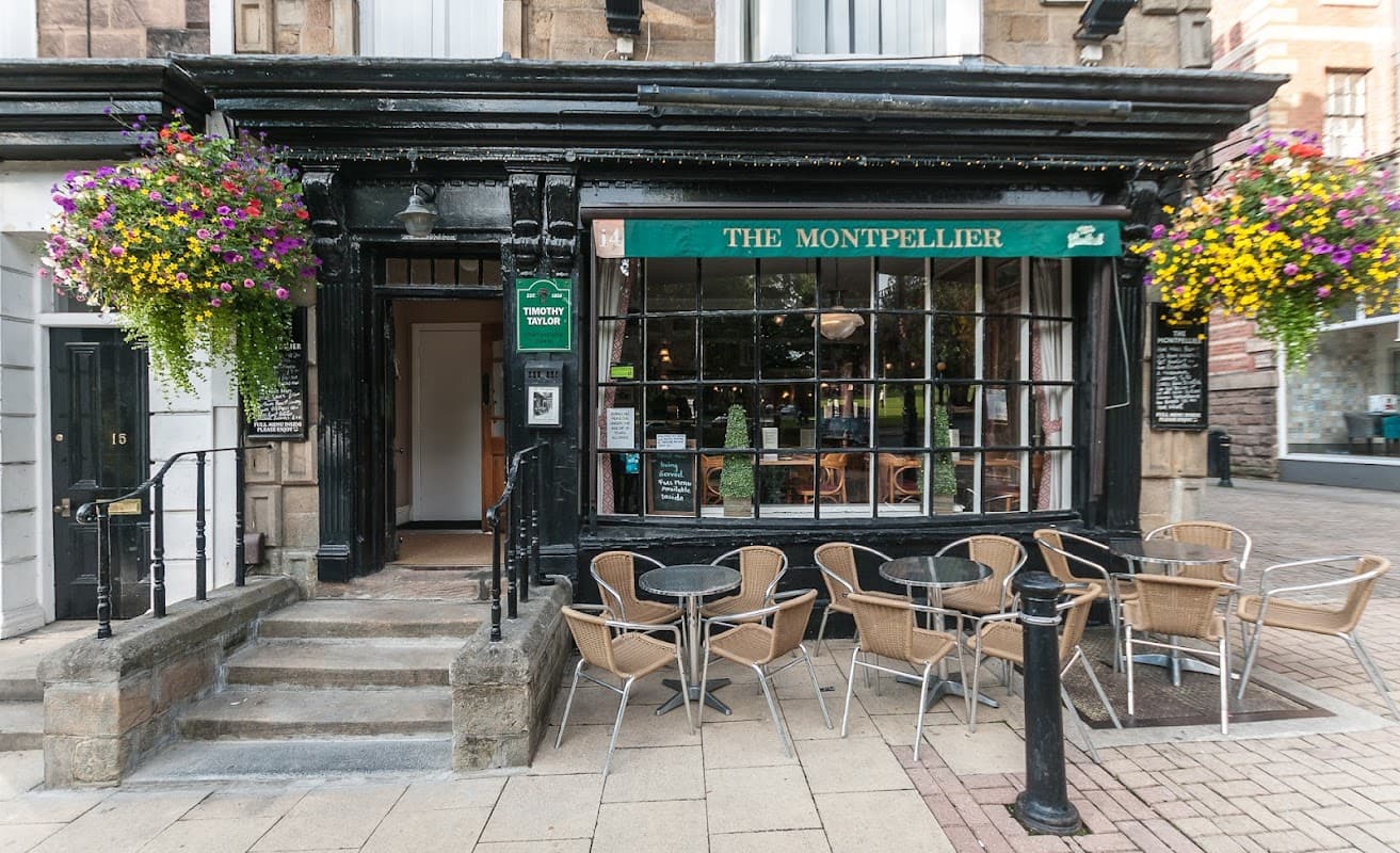 The Montpellier bar features a black facade, large windows, outdoor seating, and vibrant flower baskets.
