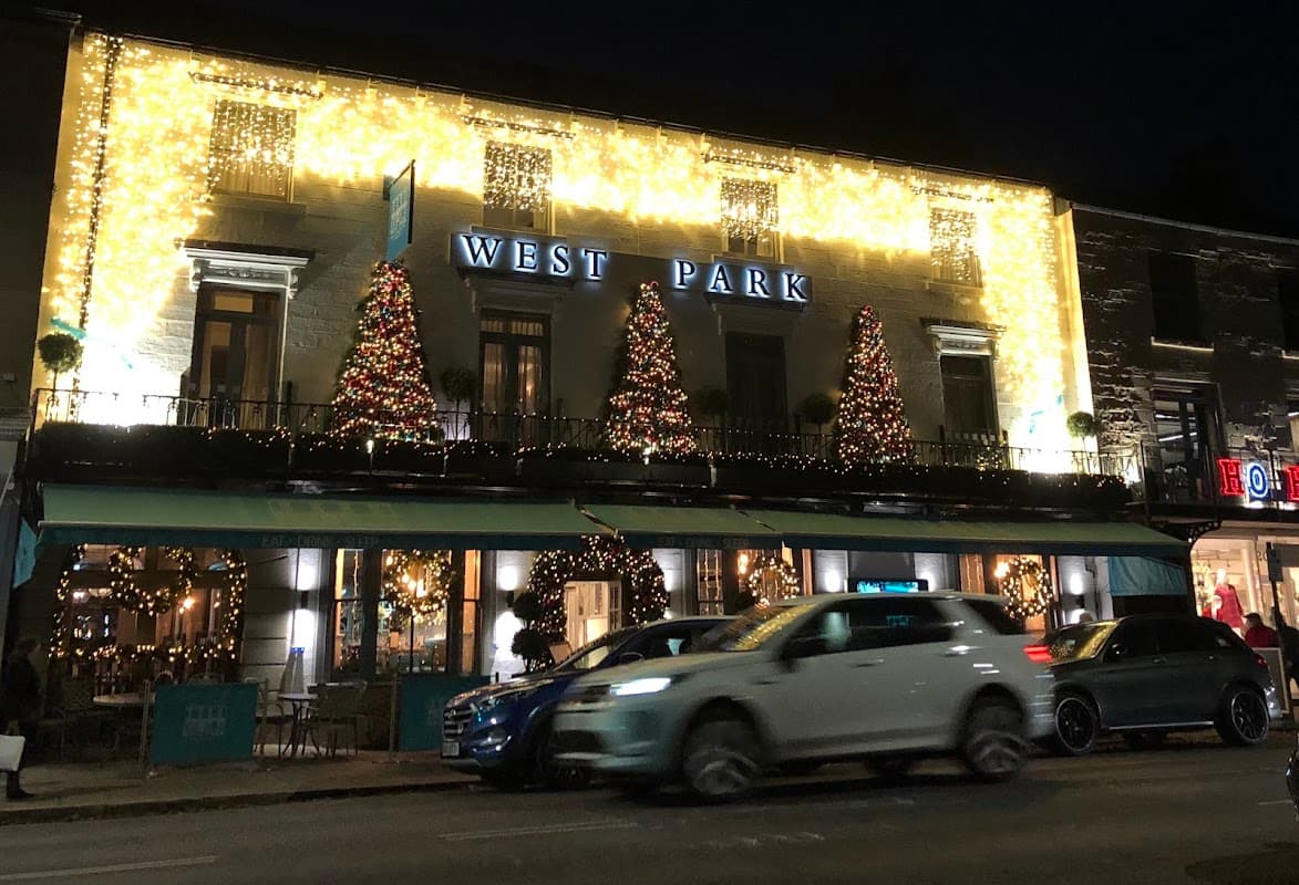 The West Park Hotel adorned with festive lights and Christmas trees, creating a warm holiday atmosphere at night.