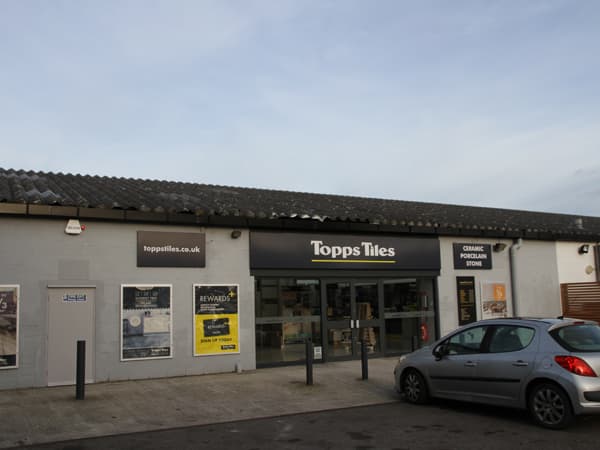 Topps Tiles store exterior in Harrogate, featuring large glass entrance and signage, with parked car in front.