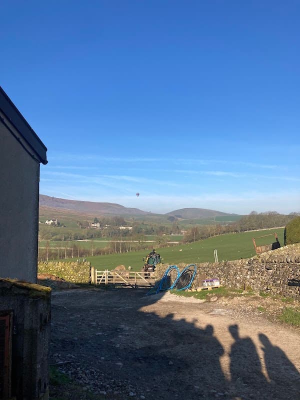 Hartlington Fencing Supplies with a clear blue sky, rolling green hills, and a distant hot air balloon.