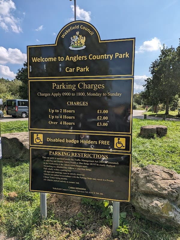 Welcome sign for Anglers Country Park with parking charges and restrictions listed, surrounded by greenery.