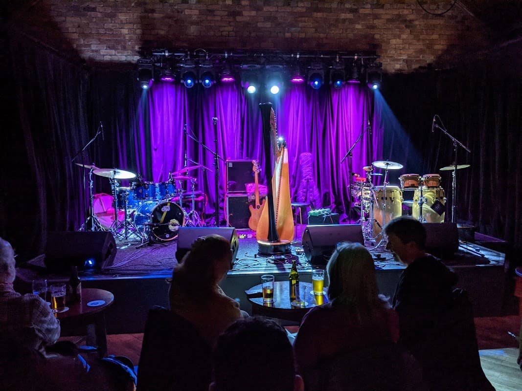 Stage set for a performance at Trades Club, featuring instruments like drums, a harp, and vibrant purple lighting.