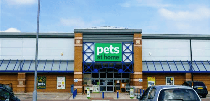 Pets at Home store entrance with blue accents and signage, surrounded by a parking lot and clear sky.