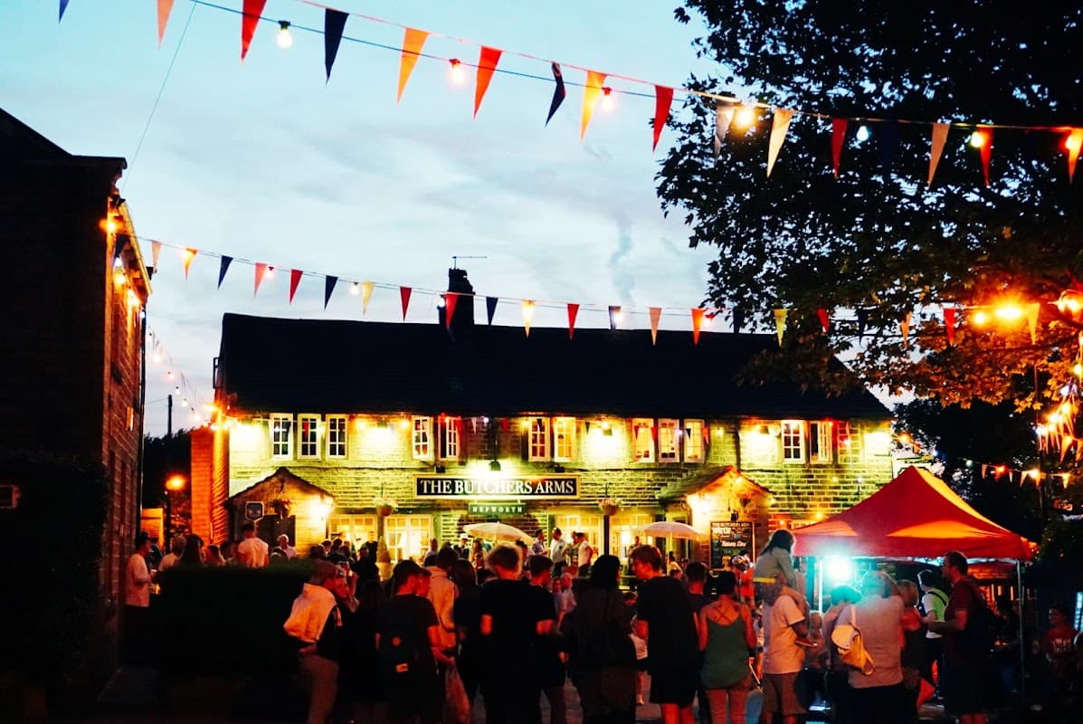 Hepworth Village Hall adorned with colorful bunting, bustling crowd, and warm lights during an evening event.