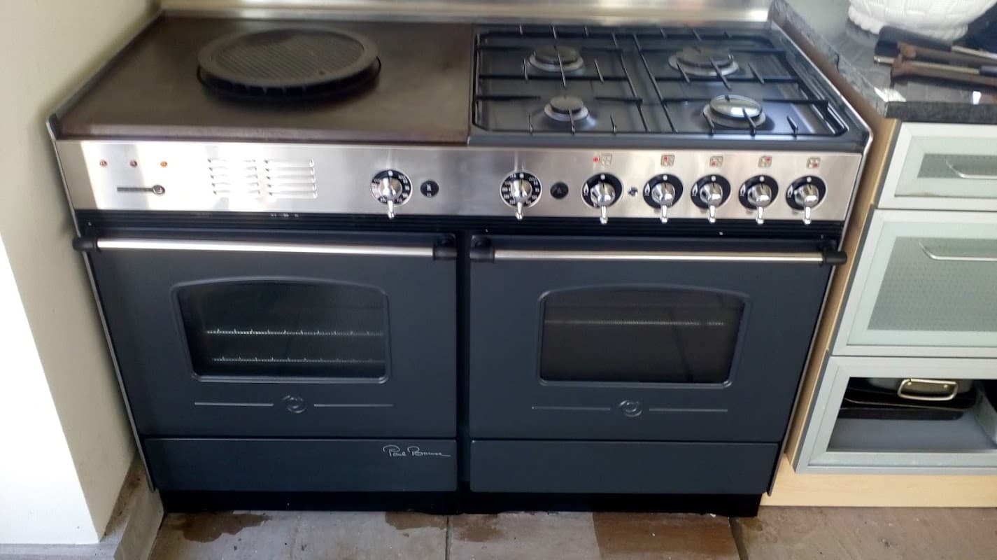 Dual oven range with gas burners, stainless steel finish, and black accents, set in a modern kitchen environment.