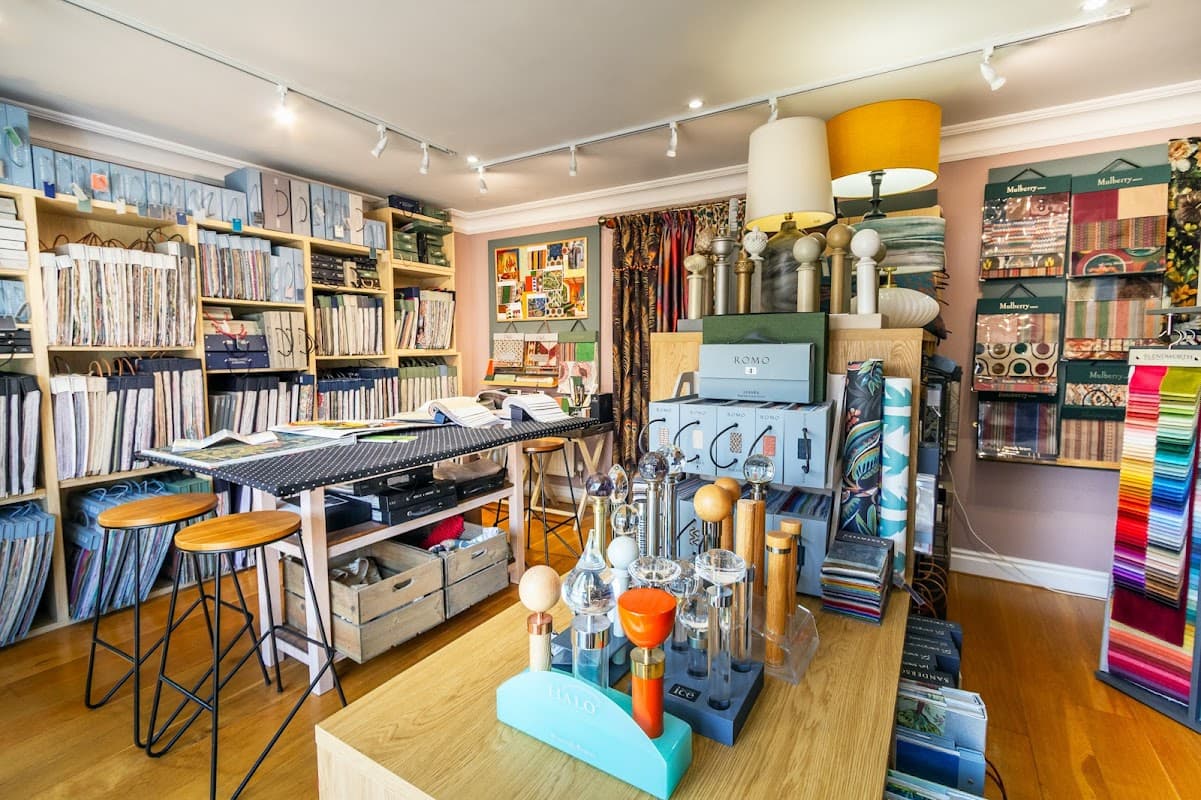 Colorful homeware displays with fabric samples, shelves filled with materials, and stylish decor elements in a cozy shop.