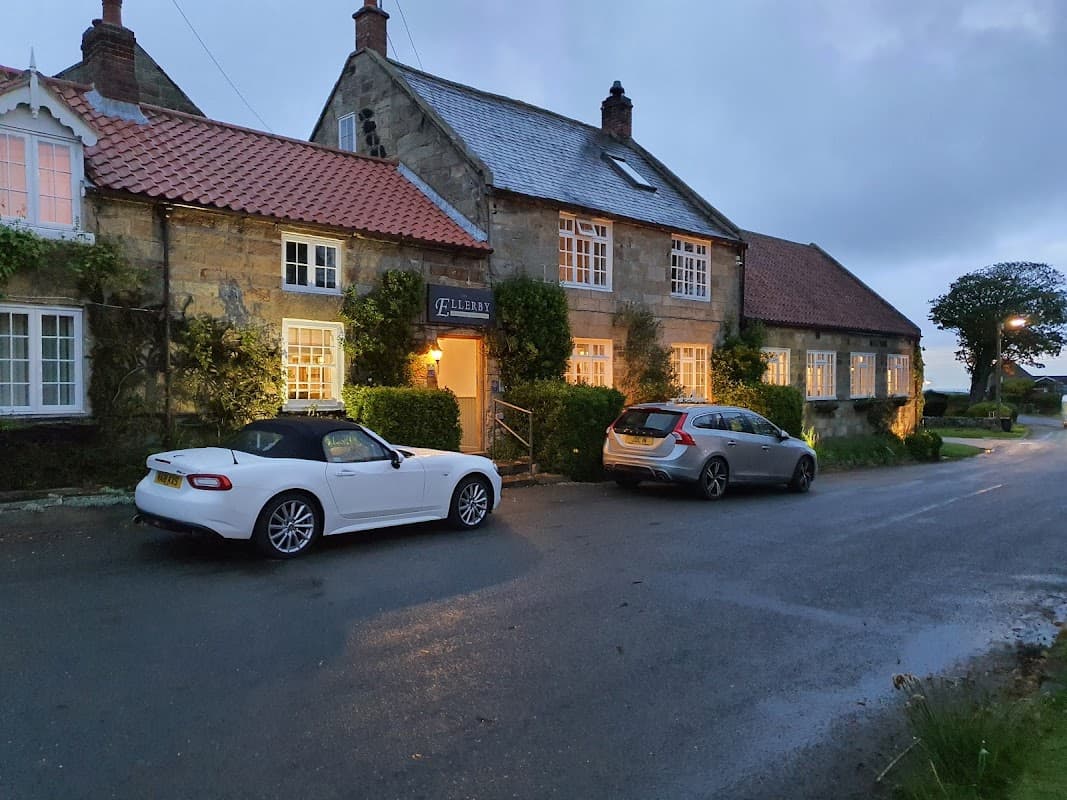 Ellerby Residential Country Inn with two parked cars, surrounded by greenery and a quiet road in Hinderwell, Yorkshire.