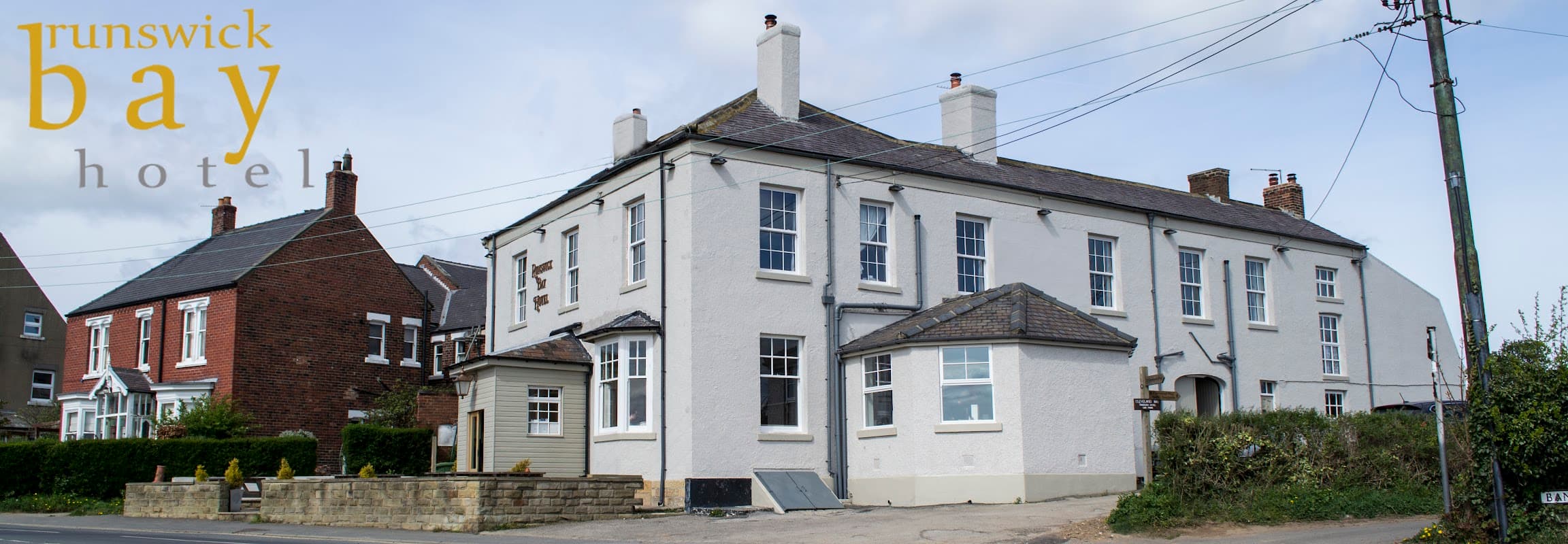 Runswick Bay Hotel's white exterior, large windows, and surrounding greenery in Hinderwell, Yorkshire.