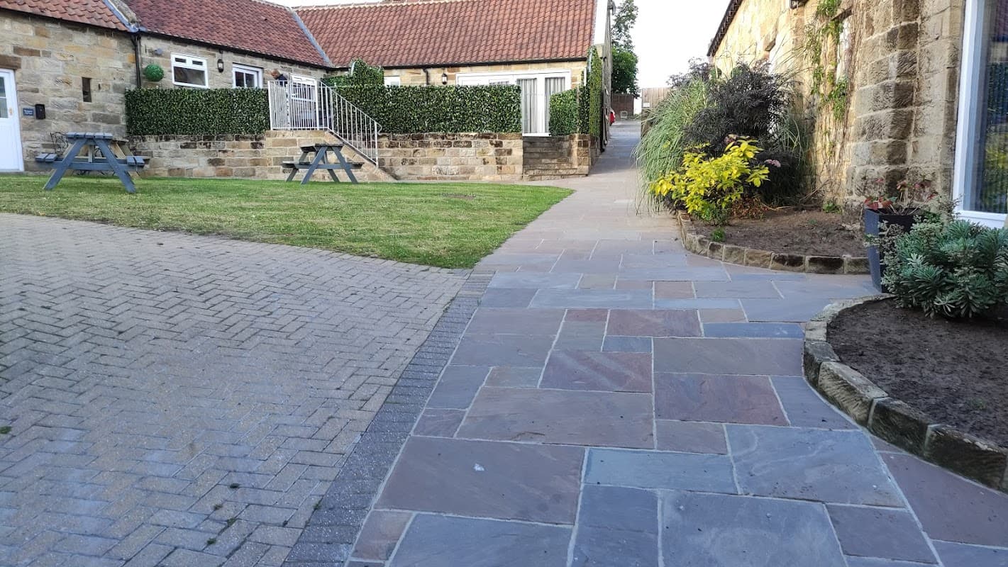 St Hilda's Complex features stone pathways, landscaped gardens, and rustic buildings with a cozy, inviting atmosphere.