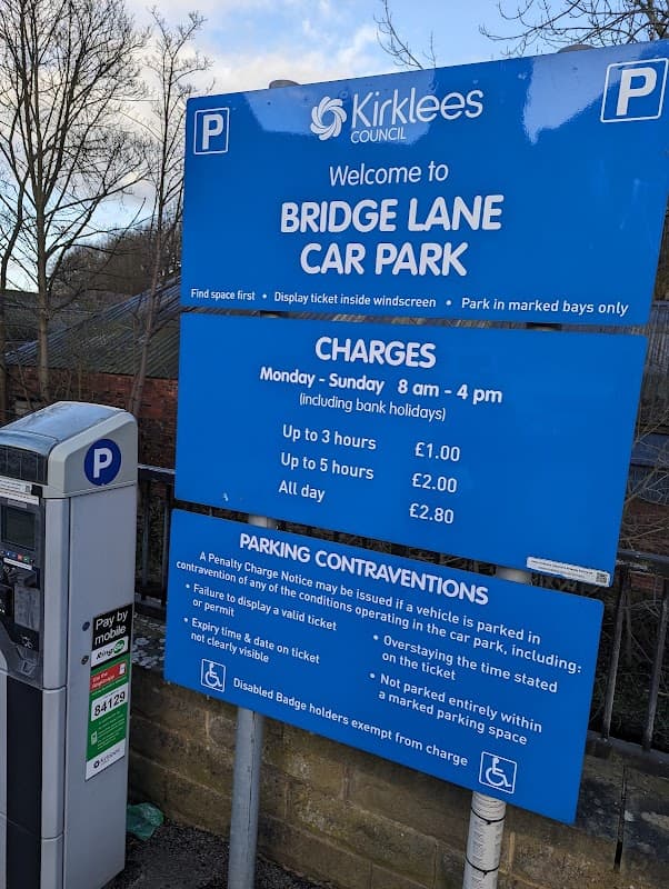 Welcome sign for Bridge Lane Car Park with parking charges and payment machine visible in Holme Valley, Yorkshire.