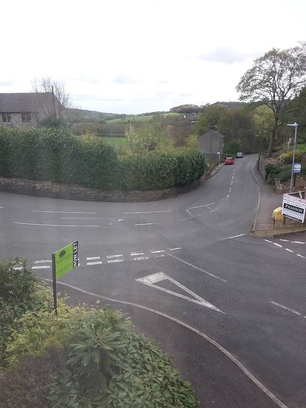 View of a quiet road intersection in Holme Valley, surrounded by greenery and a sign for "Park Side."