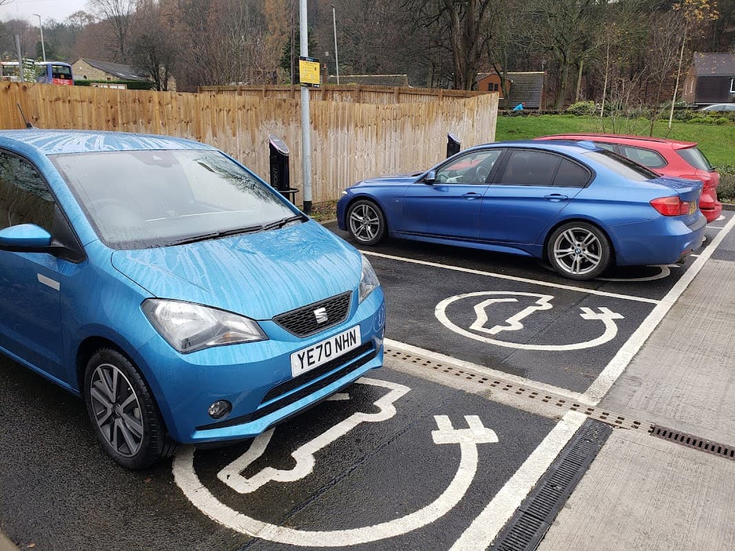 Two electric vehicles parked at a Pod Point Charging Station with designated charging spaces in Holme Valley, Yorkshire.