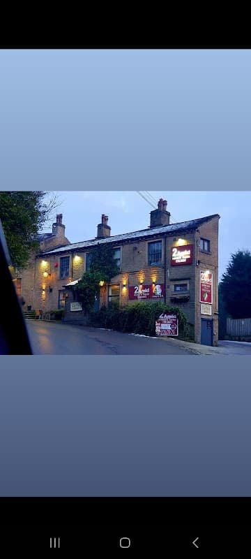 Two-story brick building with illuminated signs for "2Amici" and outdoor seating, set in a rural area at dusk.