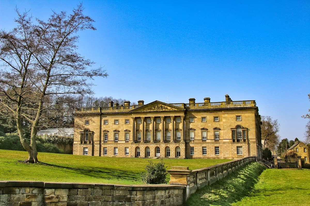 Historic Wentworth Castle Gardens with grand architecture, manicured lawns, and a clear blue sky in Hood Green, Yorkshire.