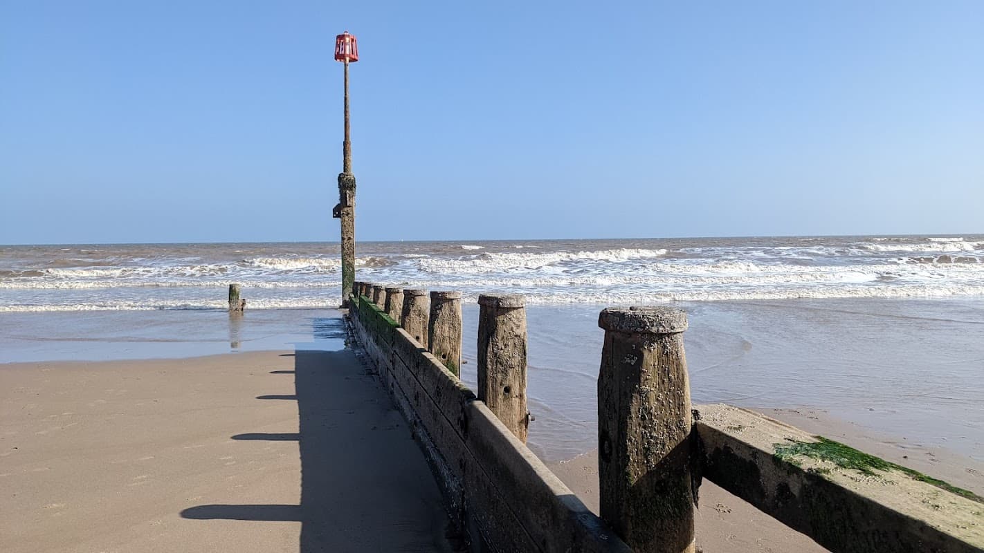 Eastgate Car Park in Hornsea, Yorkshire, with a clear blue sky and waves crashing on the sandy beach.