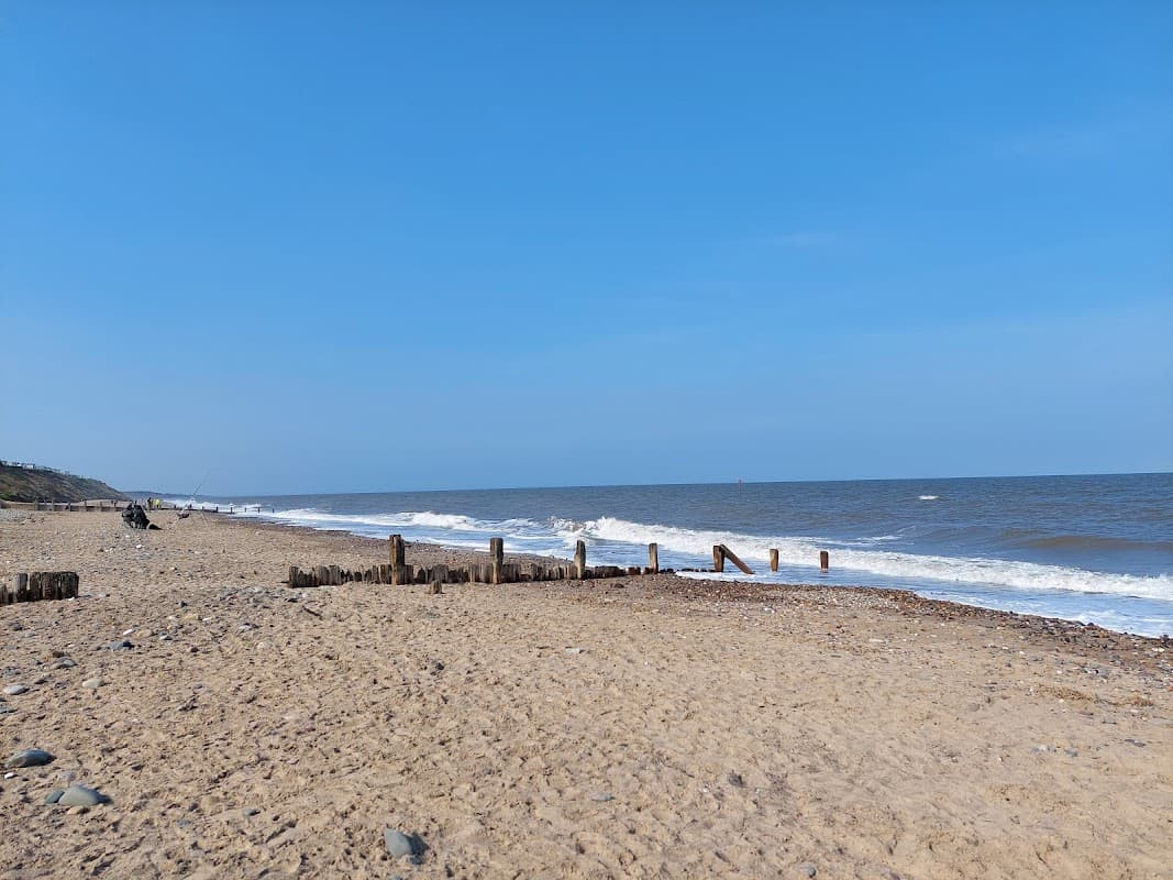 Morrow Ave Car Park near Hornsea beach, sandy shore, gentle waves, and a clear blue sky.