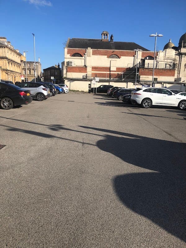 Pay & Display car park at Hull Station, featuring multiple parked cars and a clear blue sky above.