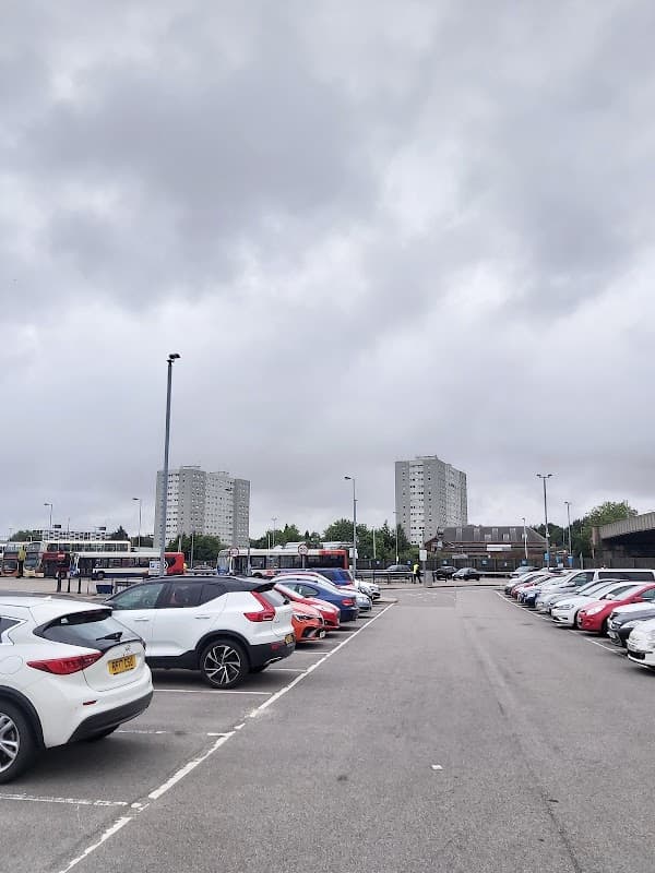 Pay & Display car park in Hull with parked cars, cloudy sky, and tall residential buildings in the background.