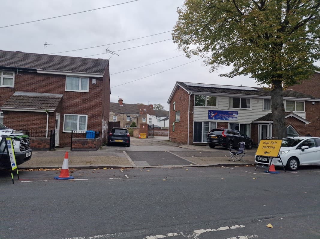 Hull Fair Parking sign with cones, nearby houses, and parked cars on a cloudy day in Yorkshire.
