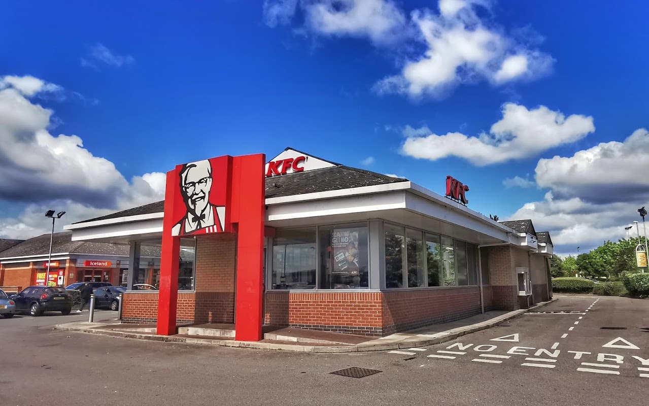 KFC restaurant with a prominent logo, blue sky, and EV charging station in Hunslet Green Retail Centre, Yorkshire.