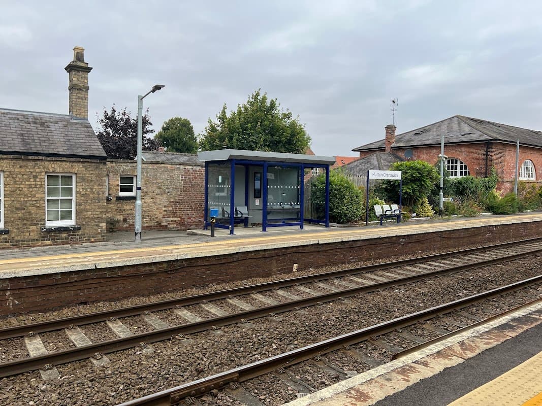 Train station platform with a blue shelter, benches, and brick buildings in Hutton Cranswick, Yorkshire.