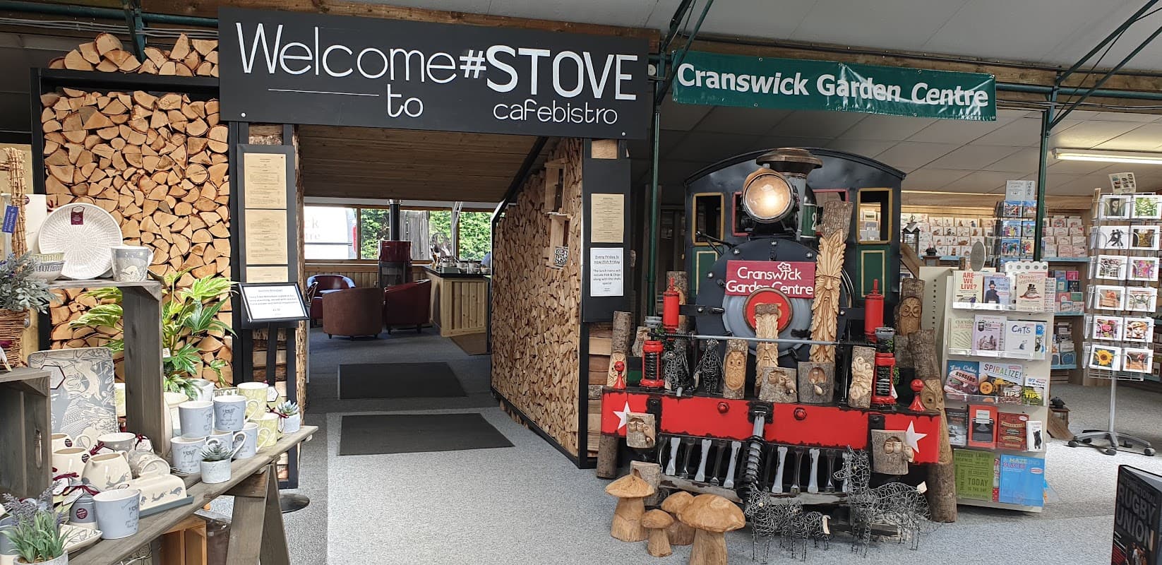 Welcome sign for #Stove Cafebistro, featuring a vintage train display and a cozy seating area with wooden decor.