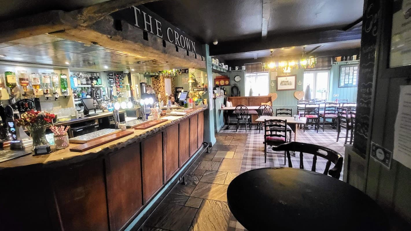 Cozy bar interior with wooden counter, drinks on display, tables, and a warm, inviting atmosphere in Hutton-le-Hole.