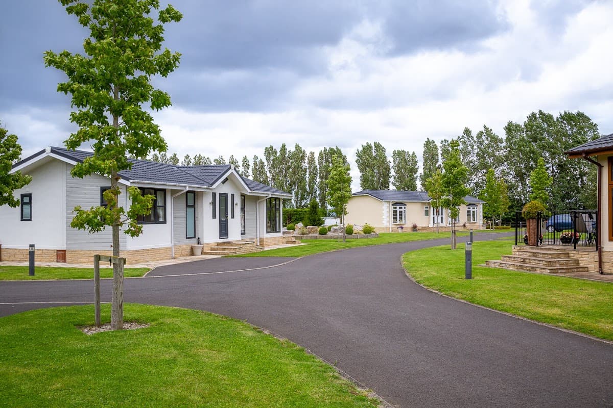 Holiday park featuring modern lodges, well-maintained lawns, and lined trees under a cloudy sky in Hutton Rudby.