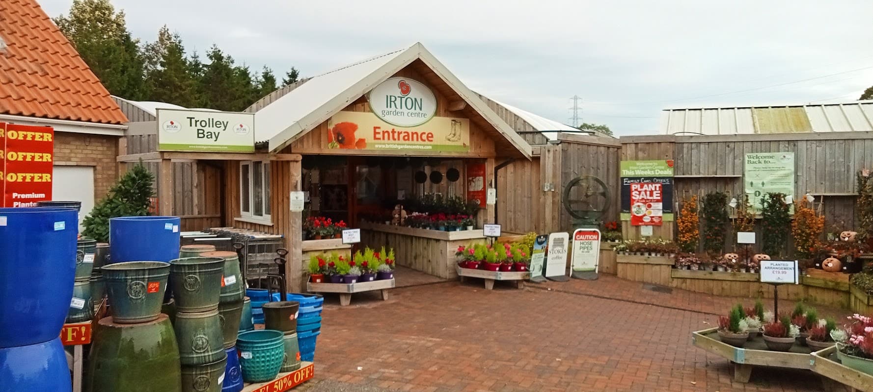 Entrance to Irton Garden Centre with colorful plants, pots, and signage, set in a charming outdoor space.