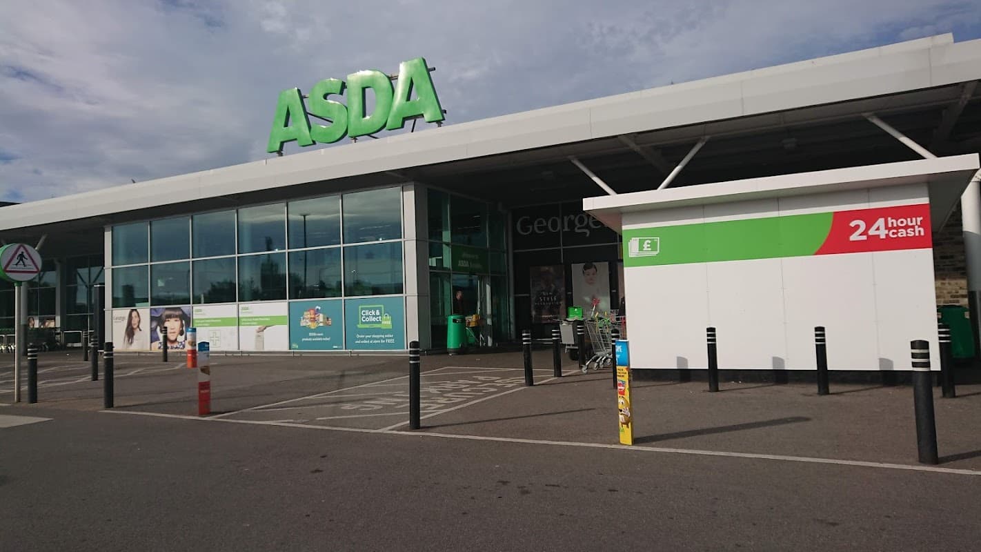 Asda Keighley Superstore entrance with large green signage, shopping carts, and a 24-hour cash machine.