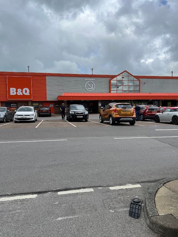 B&Q store in Keighley with parked cars, shoppers outside, and a cloudy sky overhead.