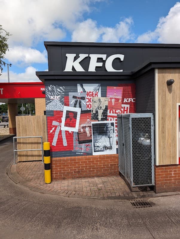KFC storefront with bold red and black signage, featuring posters and a drive-thru area in Keighley Retail Park.
