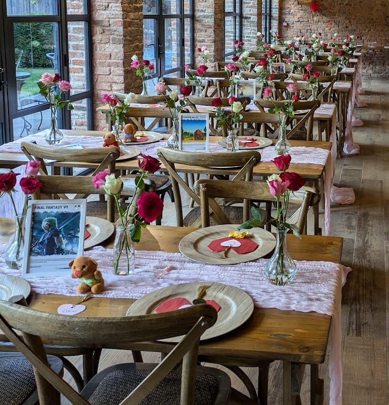 Tables set for a gathering, adorned with flowers, decorative plates, and small plush toys in a rustic, warmly lit setting.