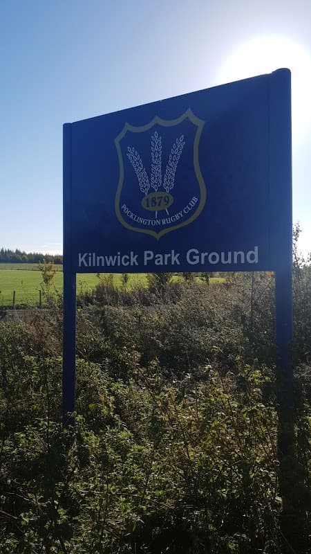 Sign for Kilnwick Park Ground with rugby club emblem, surrounded by greenery and open fields in Yorkshire.