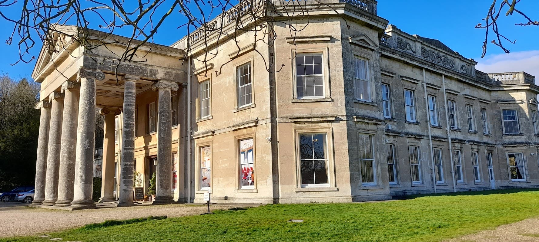 Historic hotel with grand columns, large windows, and manicured lawns set against a clear blue sky in Yorkshire.