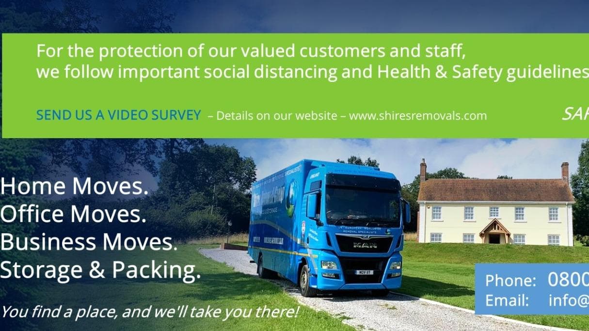 Blue removal truck parked on a driveway, with a large white house in the background and a sign promoting services.