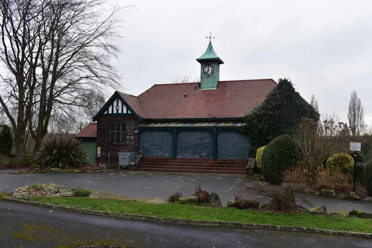 Historic building with a clock tower, surrounded by greenery and parking spaces at Vale Head Park, Kinsley, Yorkshire.