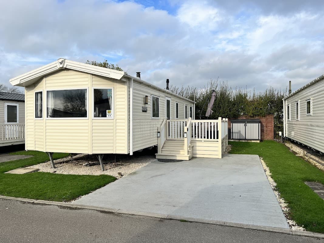 Holiday park caravan with a deck, surrounded by greenery and other caravans in Kirby Misperton, Yorkshire.