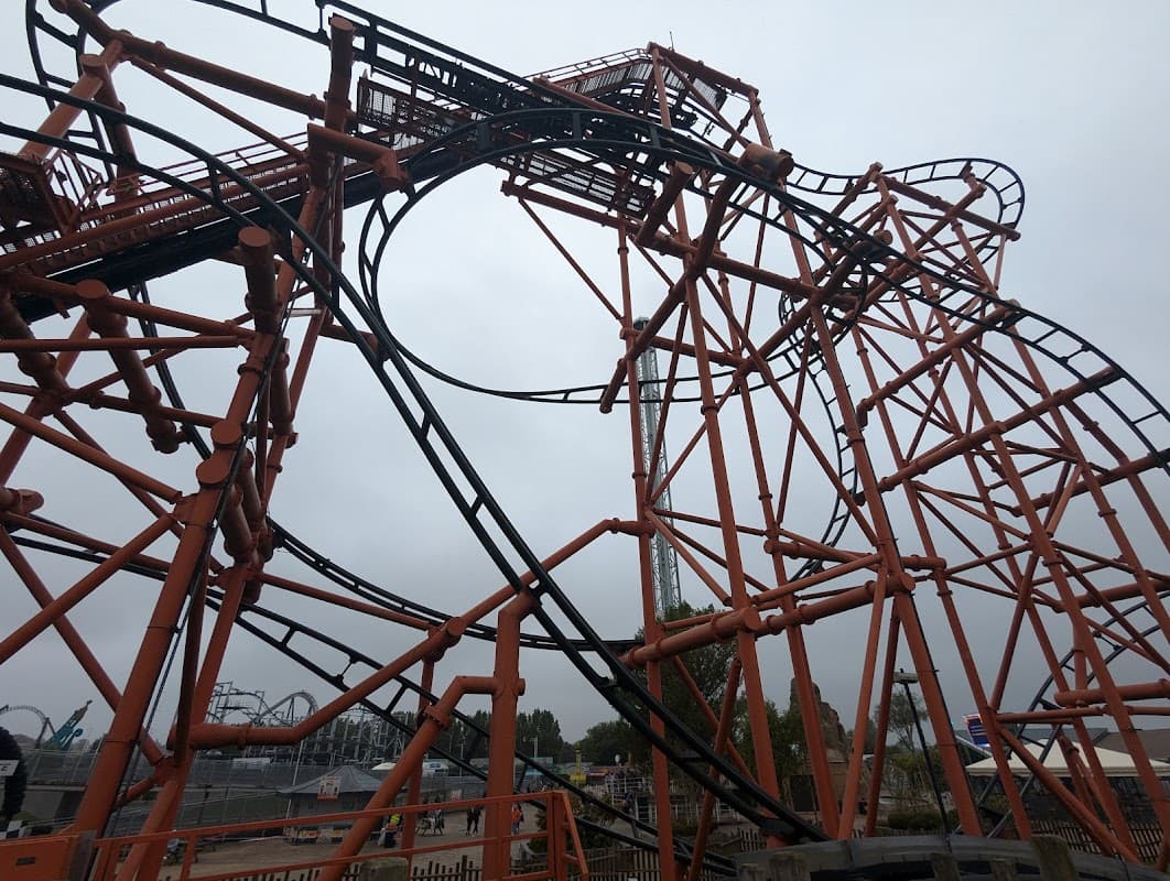 Orange roller coaster structure with loops and twists against a cloudy sky in Kirby Misperton, Yorkshire.