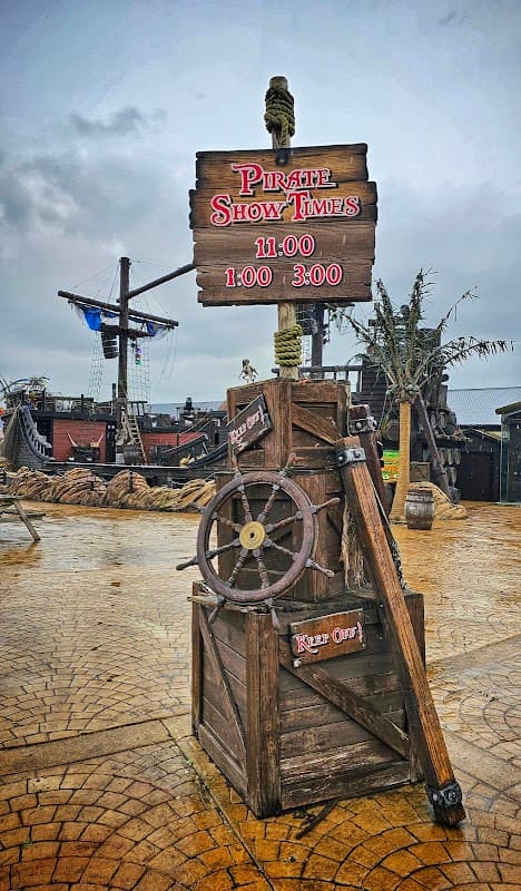 Signpost displaying "Pirate Show Times" with showtimes at 11:00, 1:00, and 3:00, set in a themed pirate area.