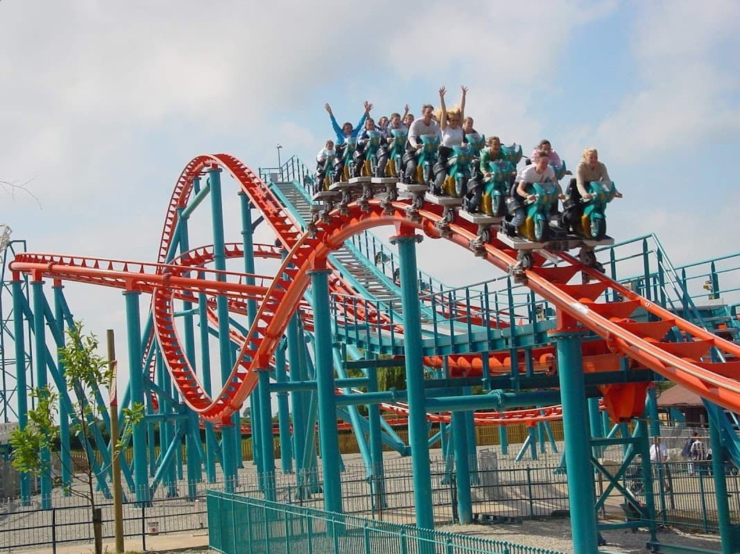 Roller coaster "Velocity" with riders in excitement, twisting tracks, and vibrant blue and red colors in Kirby Misperton.