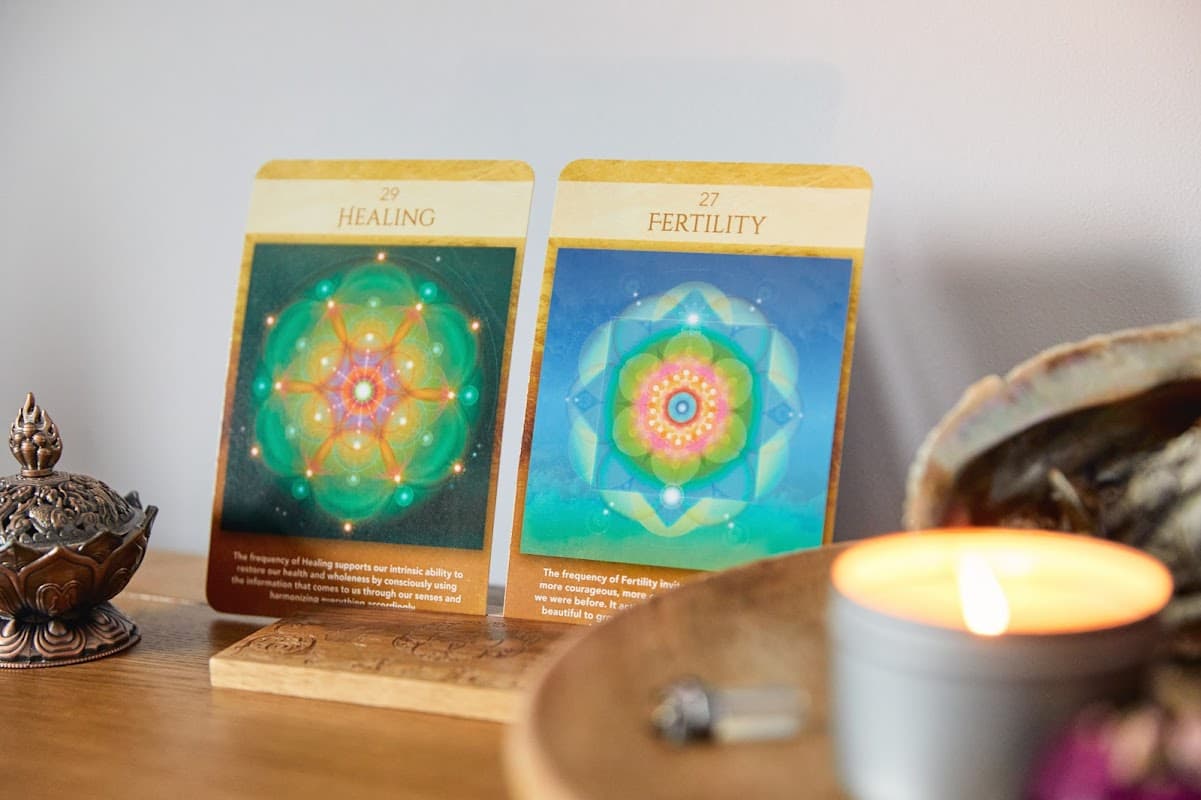 Two cards titled "Healing" and "Fertility" displayed on a wooden surface beside a lit candle and decorative items.