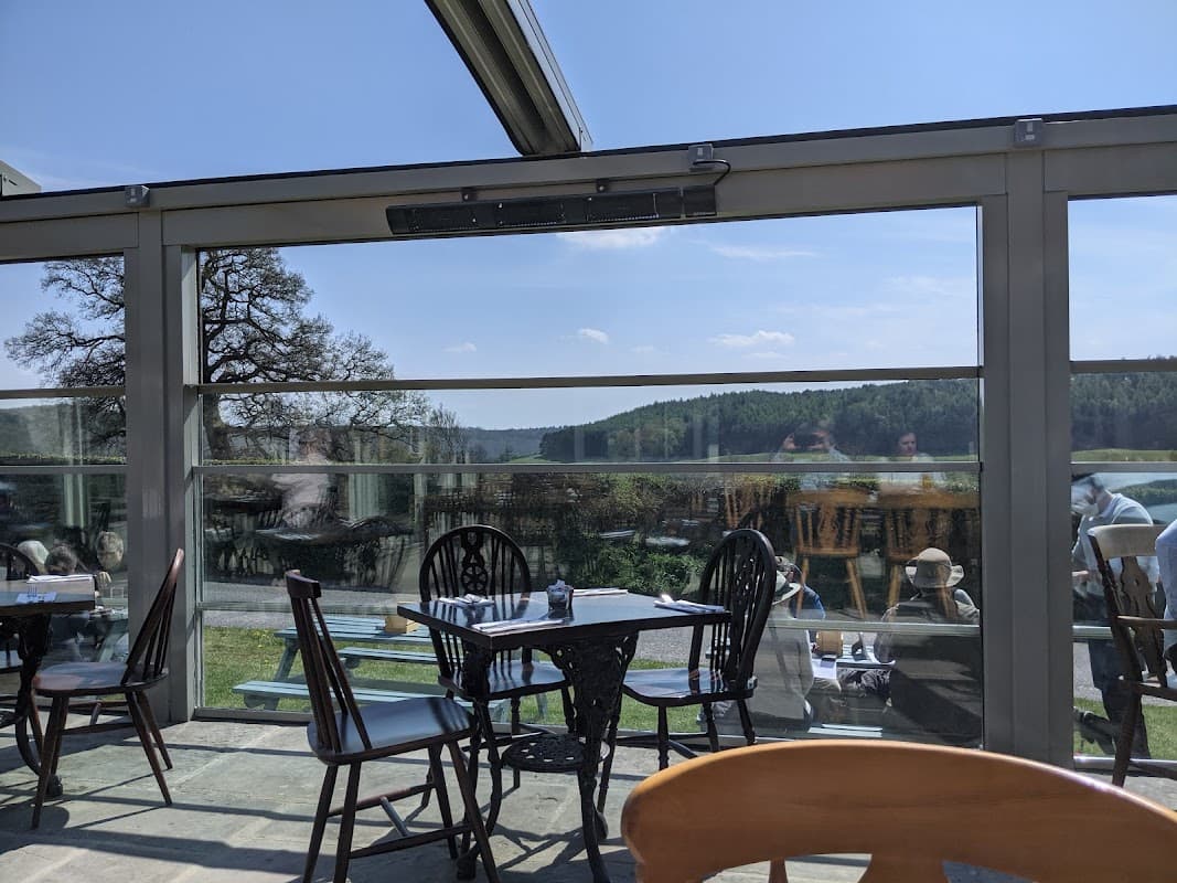 Bright interior of The Stone Trough Inn with tables and chairs, large windows showcasing a scenic view of greenery.
